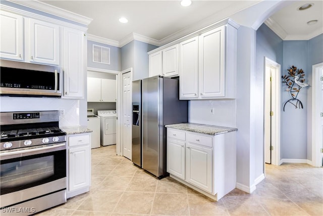 kitchen featuring ornamental molding, washer and dryer, white cabinets, and appliances with stainless steel finishes