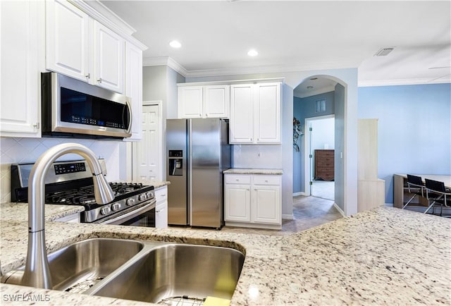 kitchen with ornamental molding, stainless steel appliances, light stone countertops, decorative backsplash, and white cabinets