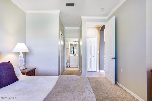 bedroom with crown molding, connected bathroom, and light carpet