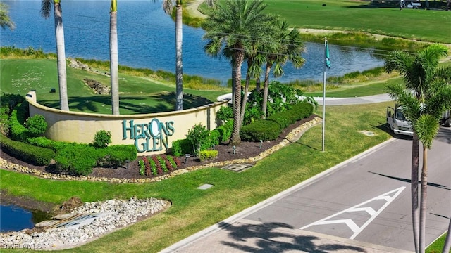 community sign featuring a lawn and a water view