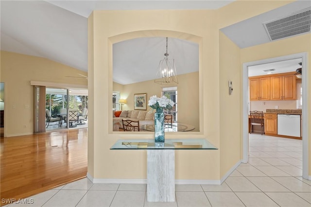 interior space featuring light tile patterned floors, ceiling fan with notable chandelier, and vaulted ceiling