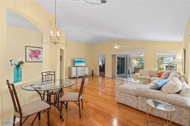 dining room with vaulted ceiling, ceiling fan with notable chandelier, and hardwood / wood-style floors