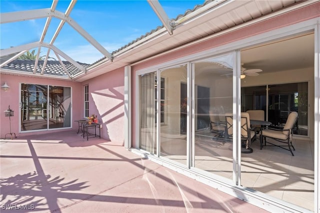 view of patio featuring ceiling fan and glass enclosure