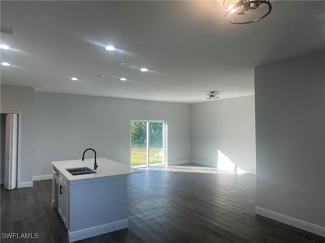 kitchen featuring white cabinetry, sink, dark hardwood / wood-style flooring, stainless steel dishwasher, and a center island with sink