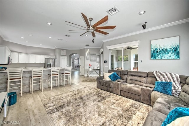 living room featuring ornamental molding, ceiling fan, and light wood-type flooring