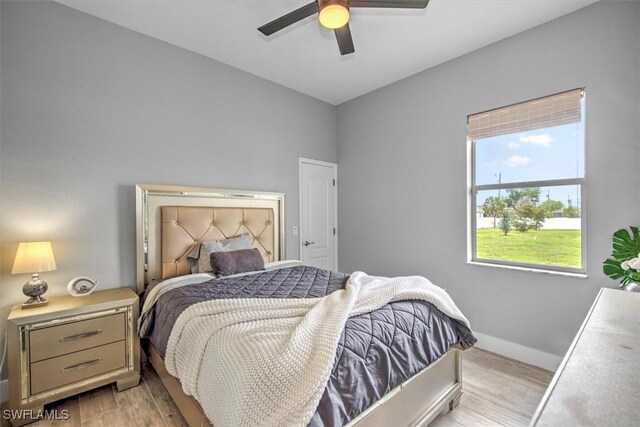 bedroom with ceiling fan, multiple windows, and light wood-type flooring