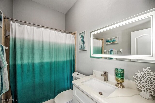 bathroom featuring vanity, curtained shower, and toilet