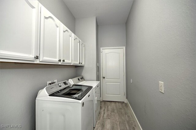 washroom featuring cabinets, separate washer and dryer, light hardwood / wood-style floors, and a textured ceiling