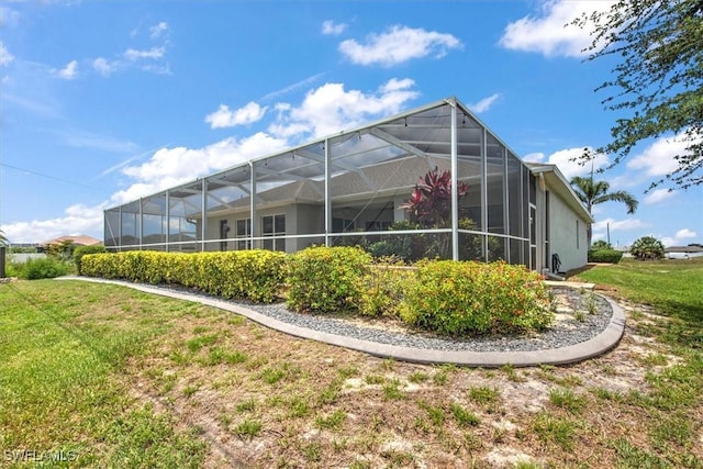 back of house featuring a lawn and glass enclosure