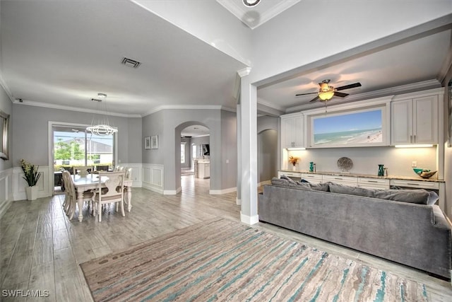 living room featuring ceiling fan with notable chandelier, ornamental molding, and light hardwood / wood-style floors