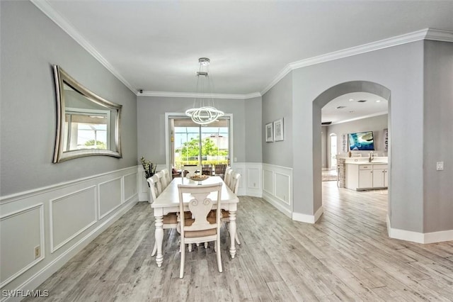 dining room featuring crown molding, sink, and light hardwood / wood-style flooring