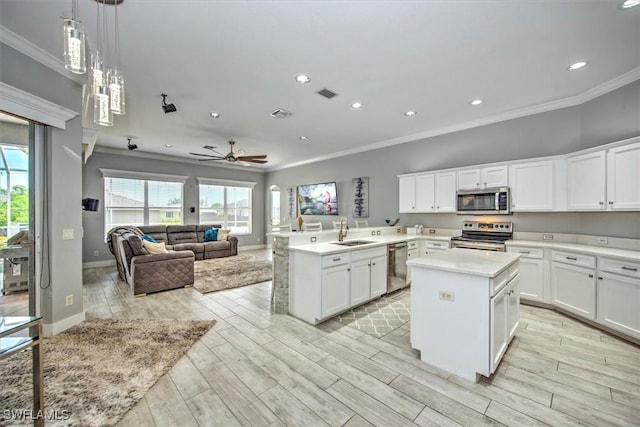 kitchen featuring appliances with stainless steel finishes, a kitchen island, kitchen peninsula, and hanging light fixtures