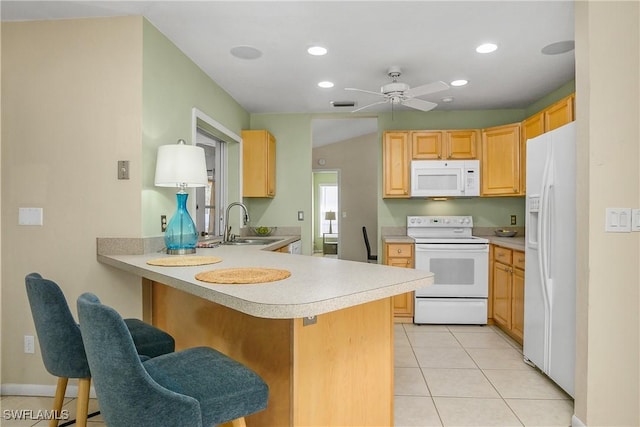 kitchen featuring sink, a breakfast bar area, light tile patterned floors, kitchen peninsula, and white appliances