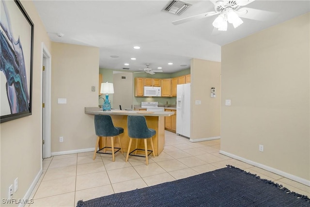 kitchen featuring light tile patterned floors, white appliances, ceiling fan, a kitchen bar, and kitchen peninsula