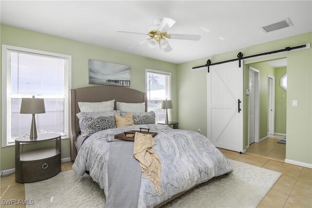 tiled bedroom with a barn door and ceiling fan