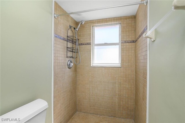 bathroom with toilet and a tile shower