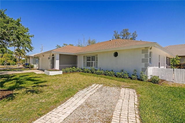 back of property featuring stucco siding, fence, and a yard