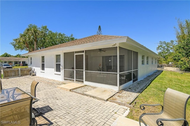 rear view of house featuring ceiling fan, fence, a sunroom, a patio area, and a lawn
