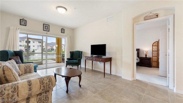 living room with light tile patterned flooring, visible vents, and baseboards