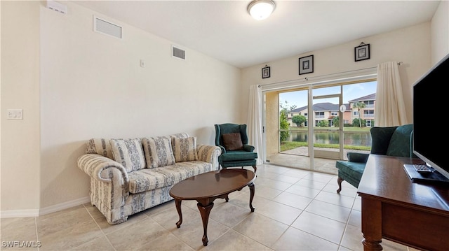 living area featuring light tile patterned floors, visible vents, and baseboards