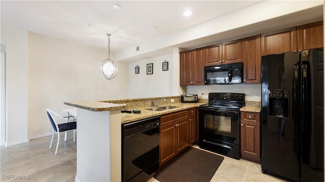 kitchen with decorative light fixtures, a peninsula, light stone countertops, black appliances, and a sink