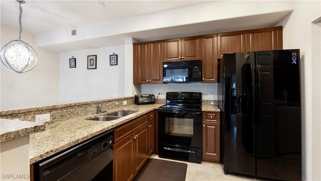 kitchen with visible vents, hanging light fixtures, light stone countertops, black appliances, and a sink