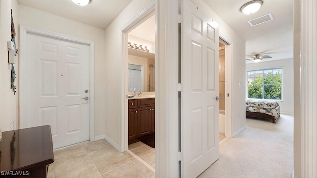 hallway with light tile patterned floors, baseboards, and visible vents