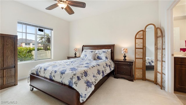 bedroom with ceiling fan, baseboards, ensuite bath, and light colored carpet