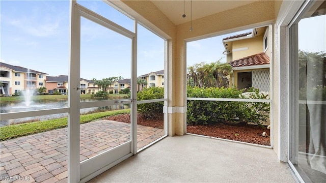 unfurnished sunroom featuring a water view and a residential view