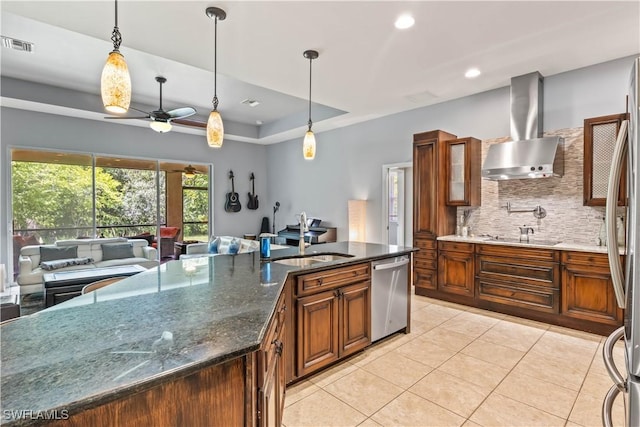 kitchen with wall chimney exhaust hood, sink, dark stone countertops, stainless steel dishwasher, and pendant lighting