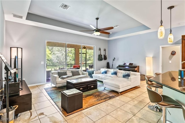 living room featuring light tile patterned floors, a raised ceiling, and ceiling fan