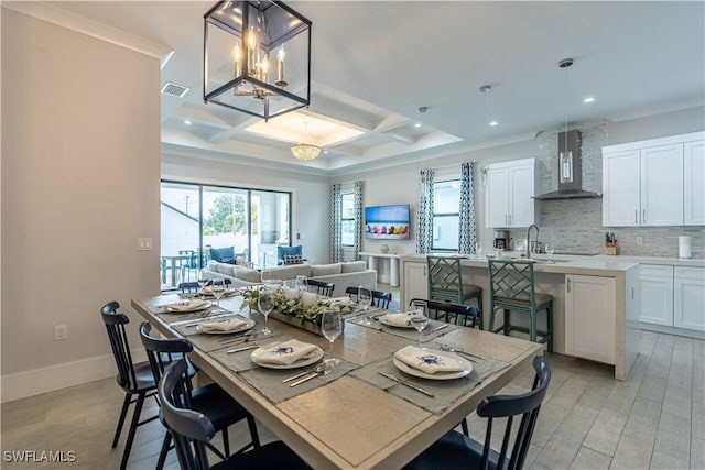 dining space featuring beamed ceiling, a chandelier, coffered ceiling, crown molding, and light hardwood / wood-style flooring