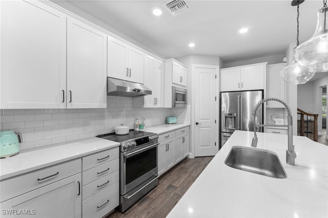 kitchen with dark hardwood / wood-style floors, pendant lighting, sink, white cabinets, and stainless steel appliances