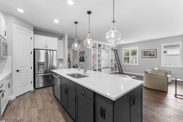 kitchen featuring sink, white cabinetry, tasteful backsplash, appliances with stainless steel finishes, and an island with sink