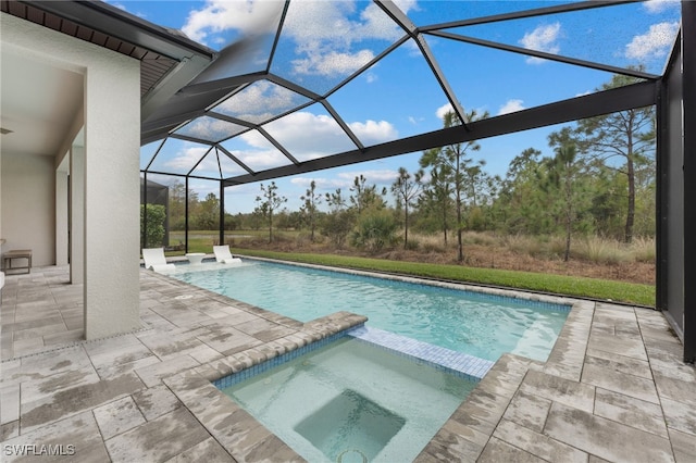 view of pool with a patio, glass enclosure, and an in ground hot tub