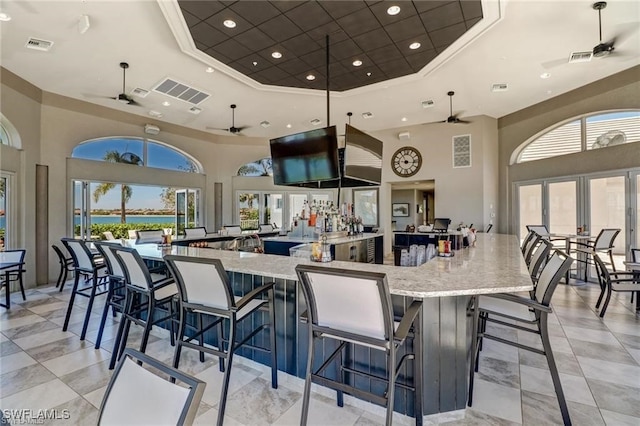 kitchen with light stone counters, a towering ceiling, ornamental molding, and a raised ceiling