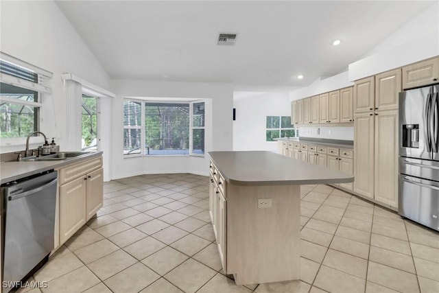 kitchen featuring lofted ceiling, sink, light tile patterned floors, appliances with stainless steel finishes, and a kitchen island