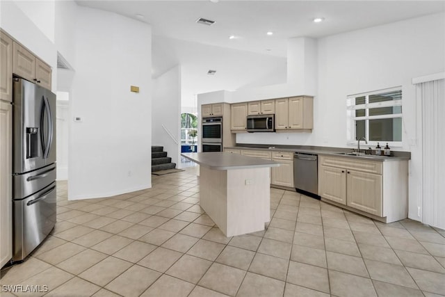 kitchen featuring sink, light tile patterned floors, a kitchen island, a towering ceiling, and stainless steel appliances