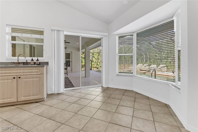 interior space with light tile patterned floors, vaulted ceiling, and sink