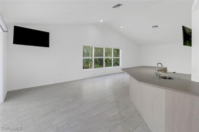 interior space featuring vaulted ceiling, sink, and light tile patterned flooring