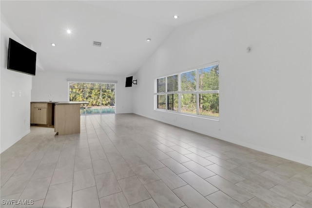 unfurnished living room featuring a wealth of natural light and high vaulted ceiling