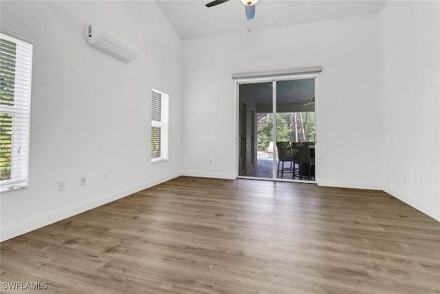 spare room featuring hardwood / wood-style floors, a wall unit AC, and ceiling fan