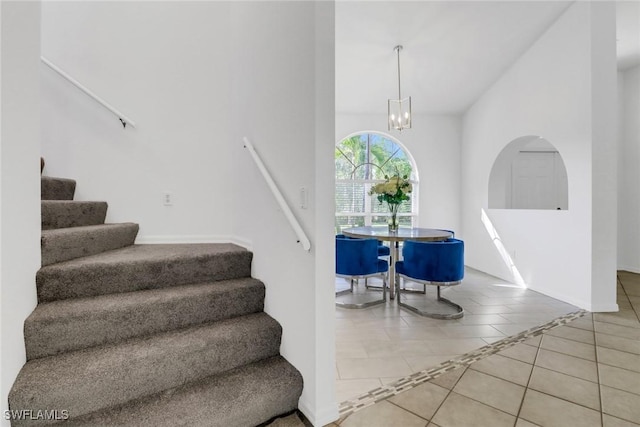 stairs with tile patterned flooring and a notable chandelier