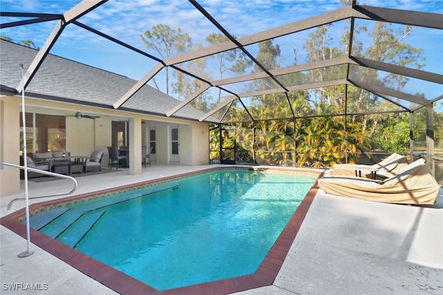 view of swimming pool with ceiling fan, a patio, an outdoor hangout area, and glass enclosure