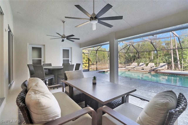 view of patio featuring ceiling fan and glass enclosure