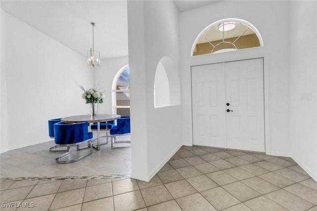 entrance foyer with light tile patterned flooring, a towering ceiling, and a chandelier