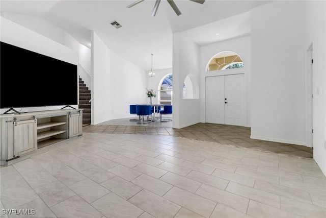 entrance foyer featuring light tile patterned floors, a towering ceiling, and ceiling fan with notable chandelier