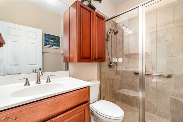 bathroom featuring vanity, toilet, and a shower with door