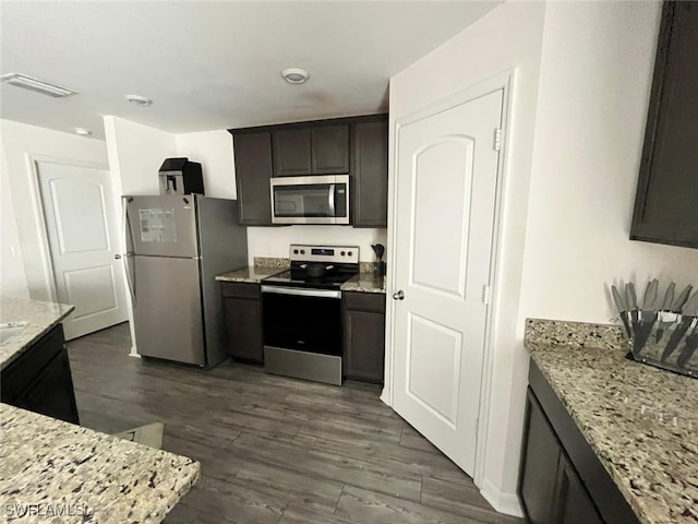 kitchen with light stone counters, appliances with stainless steel finishes, dark hardwood / wood-style floors, and dark brown cabinets