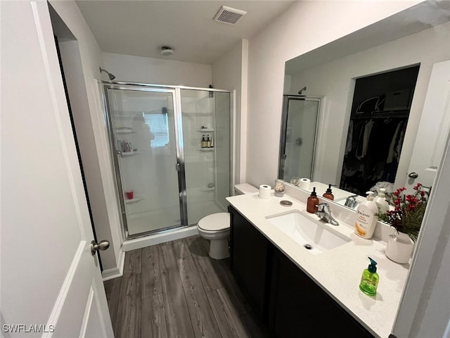 bathroom with an enclosed shower, vanity, wood-type flooring, and toilet